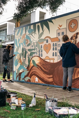 Two woman painting a mural
