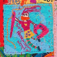 Detail of hand embroidered quilt showing a woman holding a sewing machine
