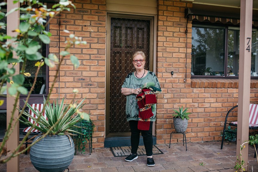 Woman standing at her front door with her knitting.