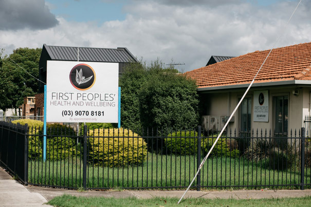 The outside of a building that is behind a black garden fence. There is a sign in the garden