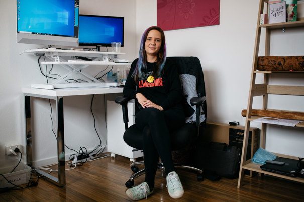 Woman sitting a here desk in front of her computer. There are two screens on the desk.