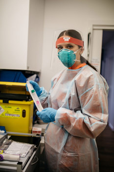 Woman wearing PPE holding COVID test