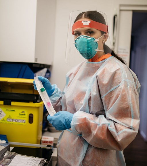 Woman wearing PPE holding COVID test