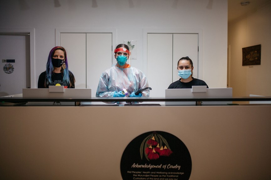 Three woman posing behind the reception desk at a medical office