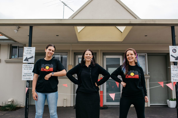Three woman standing side by side bumping elbows