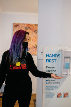 Woman using a wall hand sanitising station
