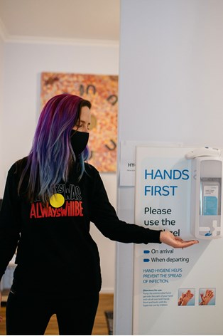 Woman using a wall hand sanitising station