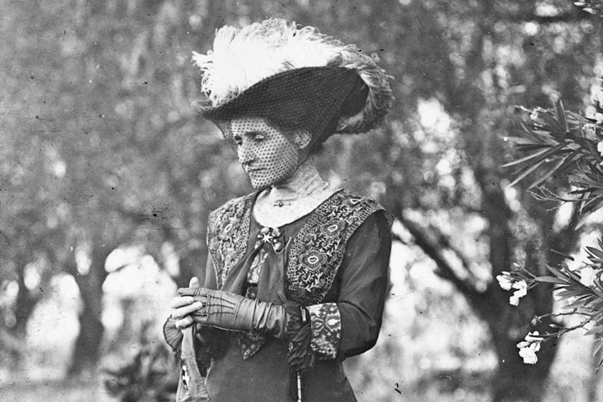 Black and white photo of a woman wearing an ornate feathered hat
