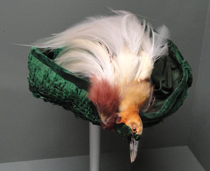 an elaborate green hat with a stuffed bird on top