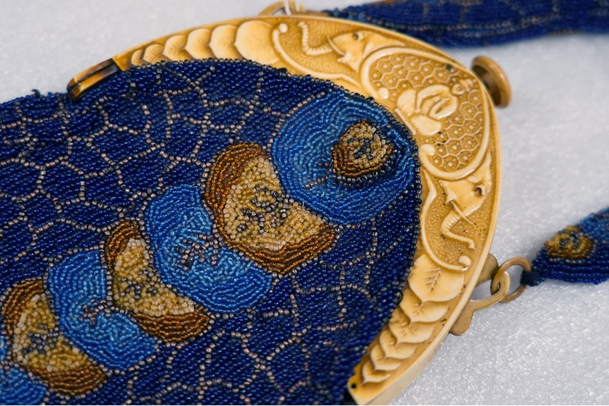 an elaborate blue beaded bag with a fake ivory band on top