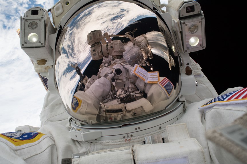 an astronaut's helmet reflects the earth from space 