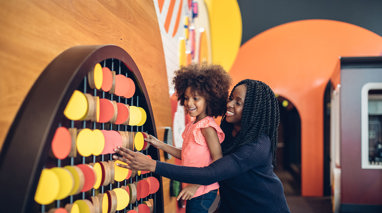 Mother and daughter playing with circular wooden blocks at the Pauline Gandel Children's Gallery, Melbourne Museum.