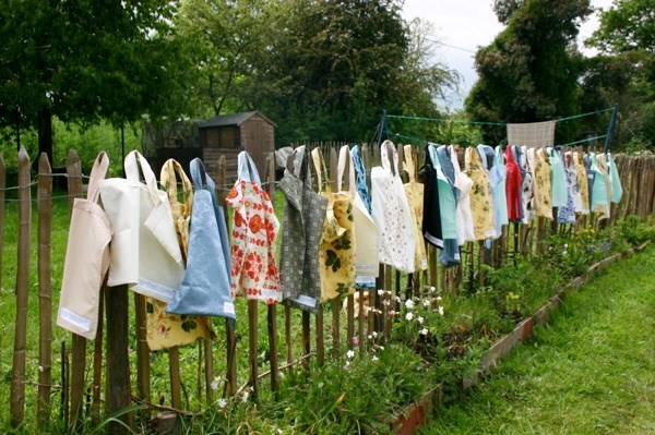 Tote bags made from recycled fabric hanging on a wooden fence
