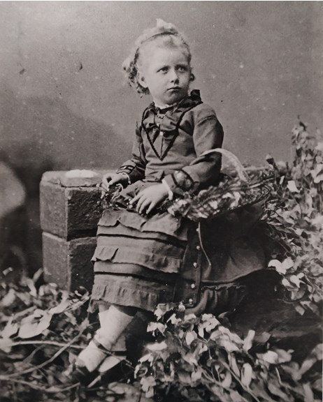 a black and white photo of a young child wearing a dress