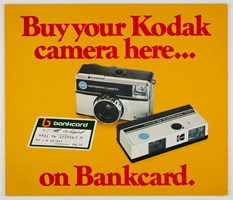 Poster with a yellow background features two different camera and a bankcard. Red text "Buy your Kodak camera here...on Bankcard"