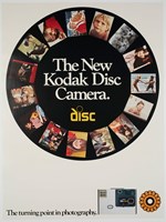 White poster with a black circle featuring photos. Text "The new Kodak disc camera. Turning point in photography" The camera is featured at the bottom of the poster.