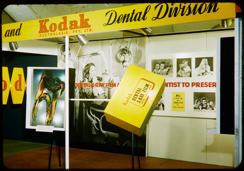 Trade show stand with yellow signage and black and white posters.
