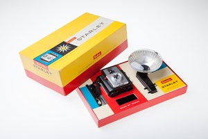 Red and yellow box with camera, flash and flash bulb, and a small brochure inside. 