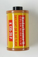 Cylindrical, terracotta-coloured metal film cartridge with label printed in red and yellow colour scheme. 