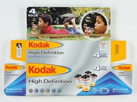 unused flat pack boxes printed in a yellow, red, white, blue and silver colour scheme with a photograph on the front of a boy blowing bubbles.