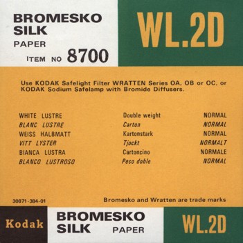 Small square printed label, printed in black, white, green and yellow colour scheme.