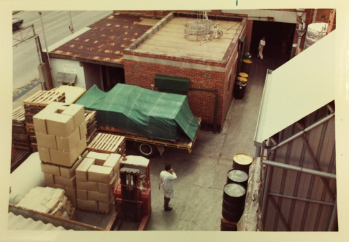 Ariel view of factory buildings and yard. A man is standing next to a forklift and plates