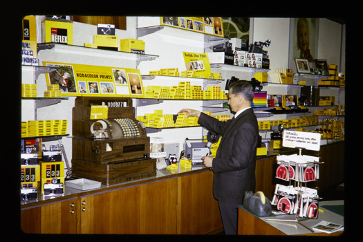 Man inside a Kodak retail shop picking a product off the shelf