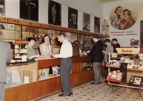 People in a shop that sells cameras, film and photographic equipment.