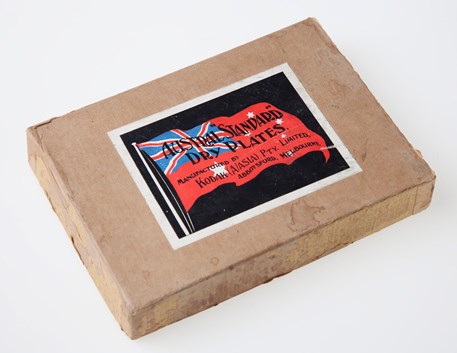 Brown cardboard box with black label with a red flag and text