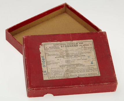 Red box with the lid open to reveal the empty box. Has white paper label with black print on the front.