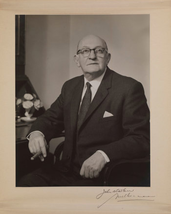 Portrait of man sitting holding a cigar and wearing glasses