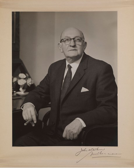Portrait of man sitting holding a cigar and wearing glasses