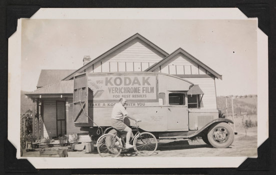 Man riding a bike past a delivery van parked outside a house