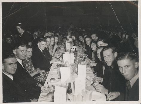 Group of men and woman sitting at long function table