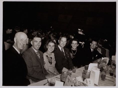 Group of men and woman sitting at long function table