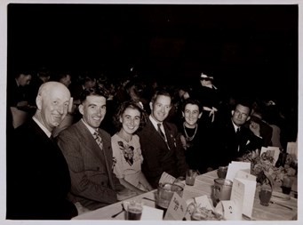 Group of men and woman sitting at long function table