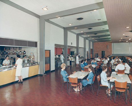 Large room with people seated at many tables.
