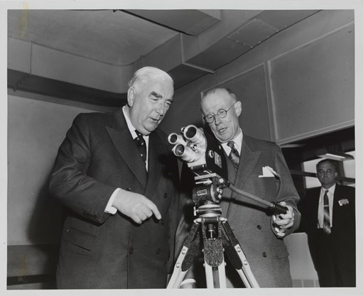 Two men looking a small movie camera