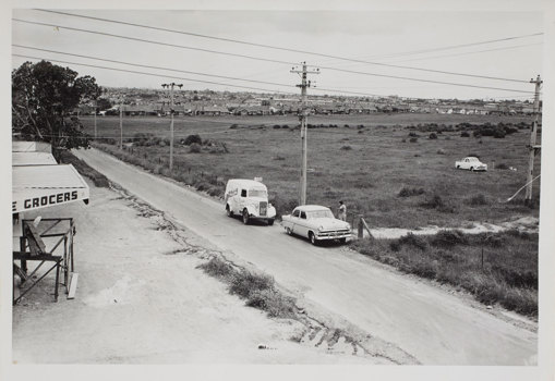 Two cars on country road with fields in background