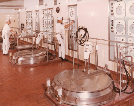 People in white coats in front of wall of controls 
