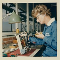 Woman using a screw driver to construct small electronic object