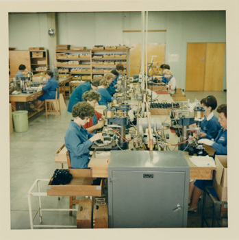 Woman sitting a tables putting together cameras