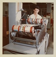 Worker standing with colour prints on rollers