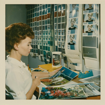Woman wearing white looking at large print photographs