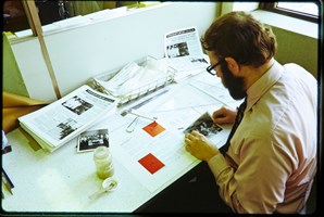Man sitting at a desk gluing images to a newletter