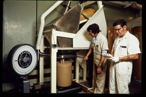 Two men in white overalls using industrial scales