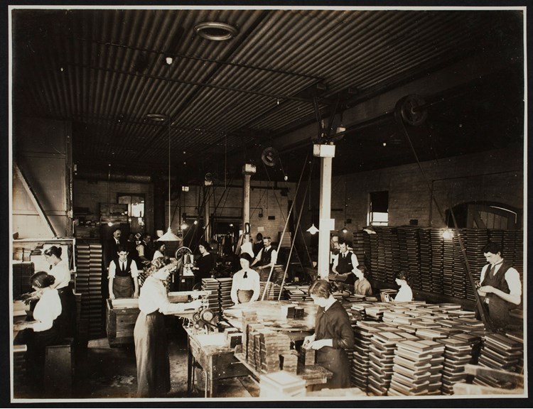 Workers surrounded by tables holding picture frames