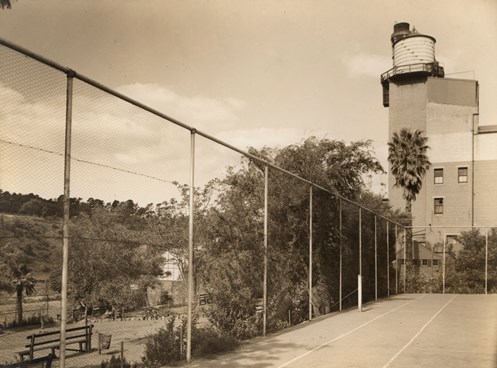 Tennis court with factory building in background