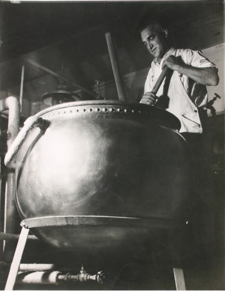Man standing over large spherical vat