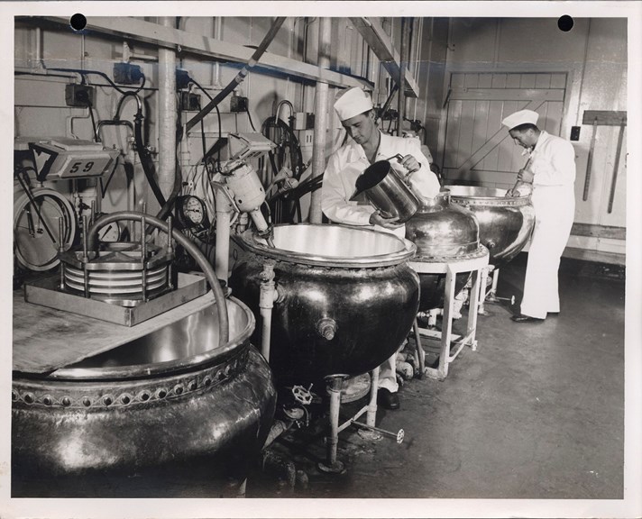 Two workers with four semi-spherical kettles.